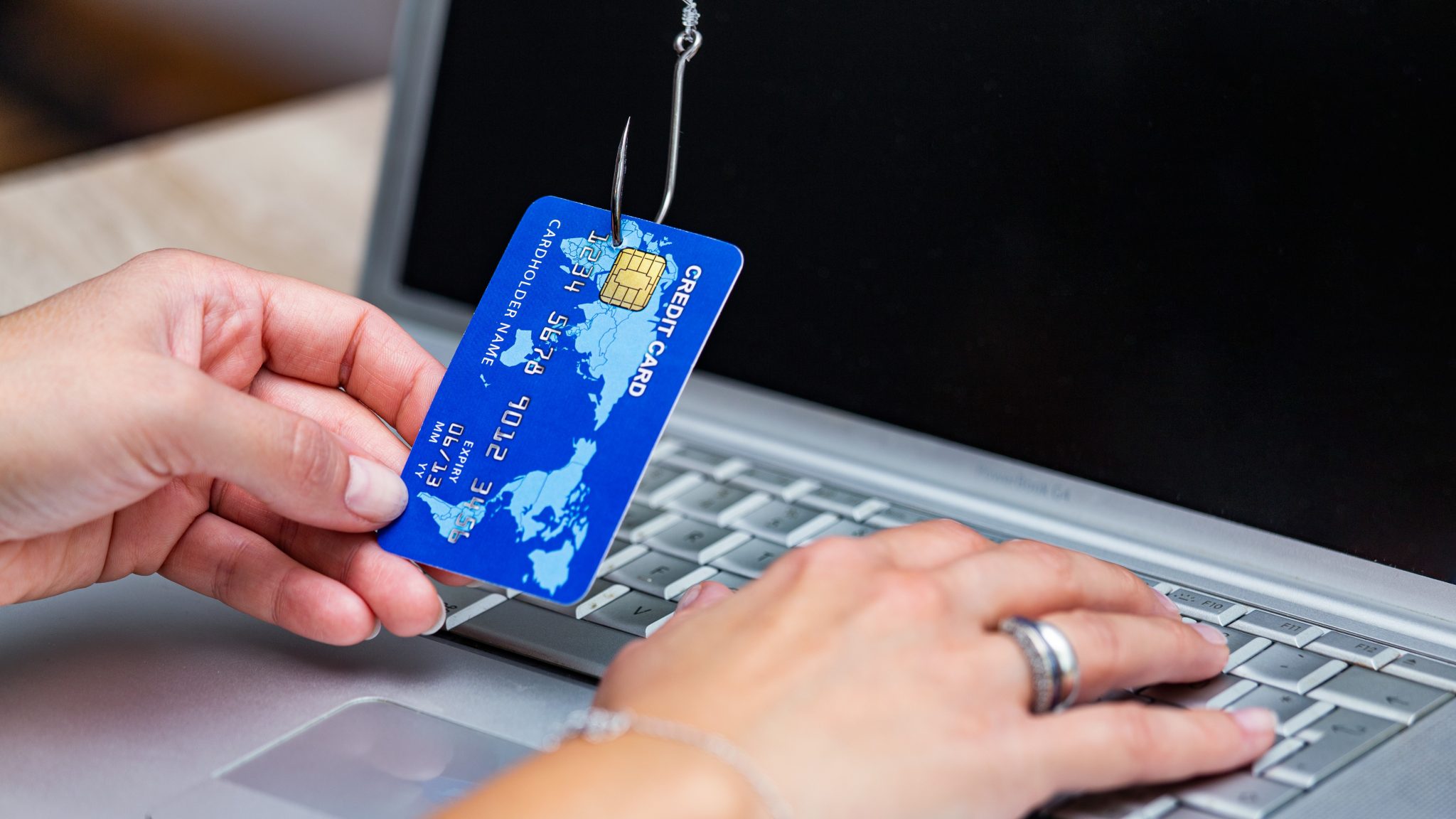 Credit card phishing. Phishing scam with credit card in fishing hook. Woman typing her credit card information on scam site