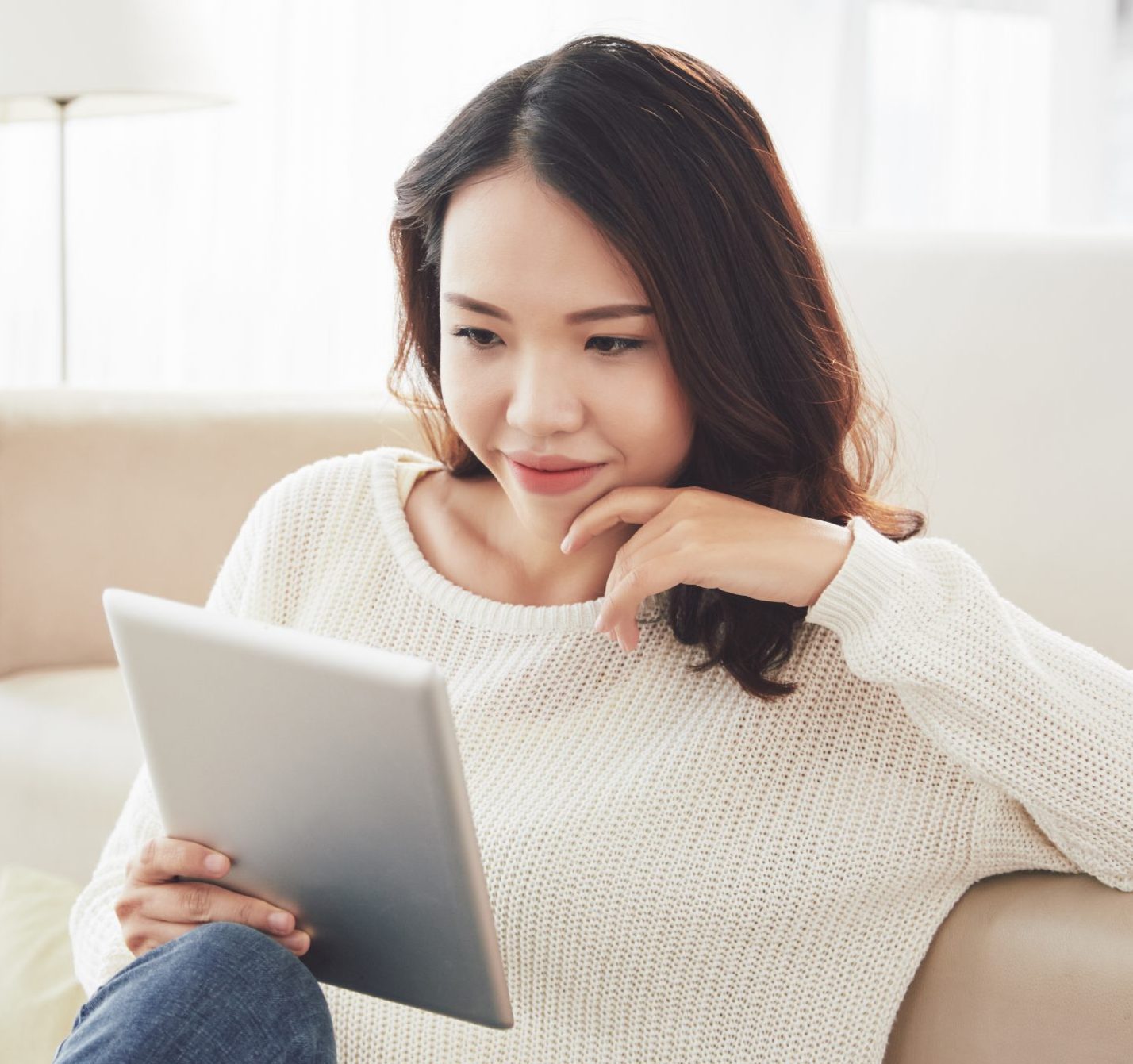 young woman smiling reading interesting web page content on tablet computer