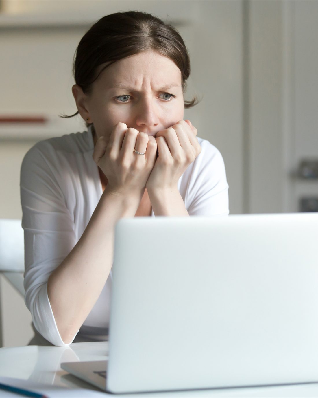 woman chewing nails looking at laptop nervous about website maintenance