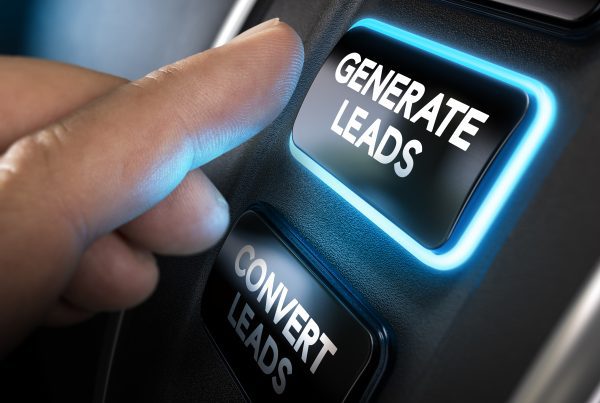 Hand about to press a generate leads button with blue light over black background.