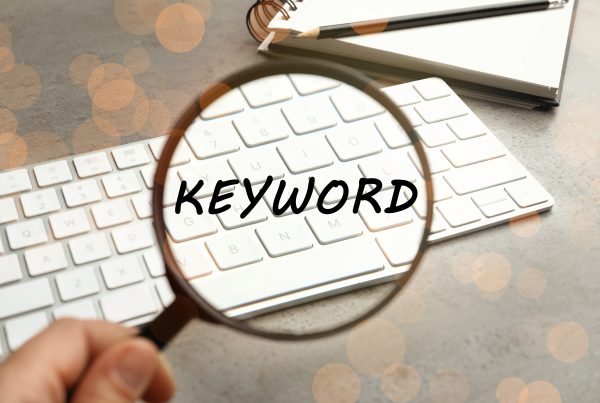 Woman looking at keyboard through magnifying glass showing closeup of keyword for research